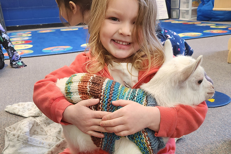 Happy girl hugging a goat
