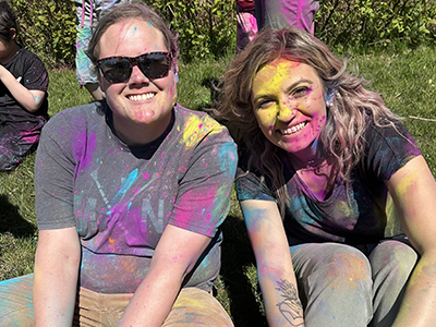 Two teachers covered in colored powder after fun outdoor activity