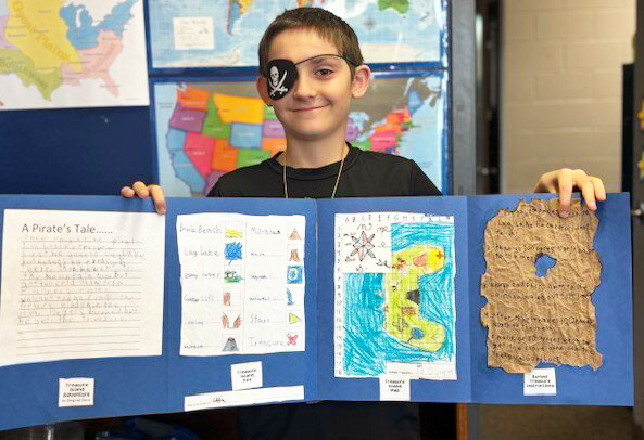 School boy proudly holding up a poster project