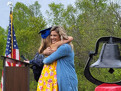 Female graduate hugging a woman